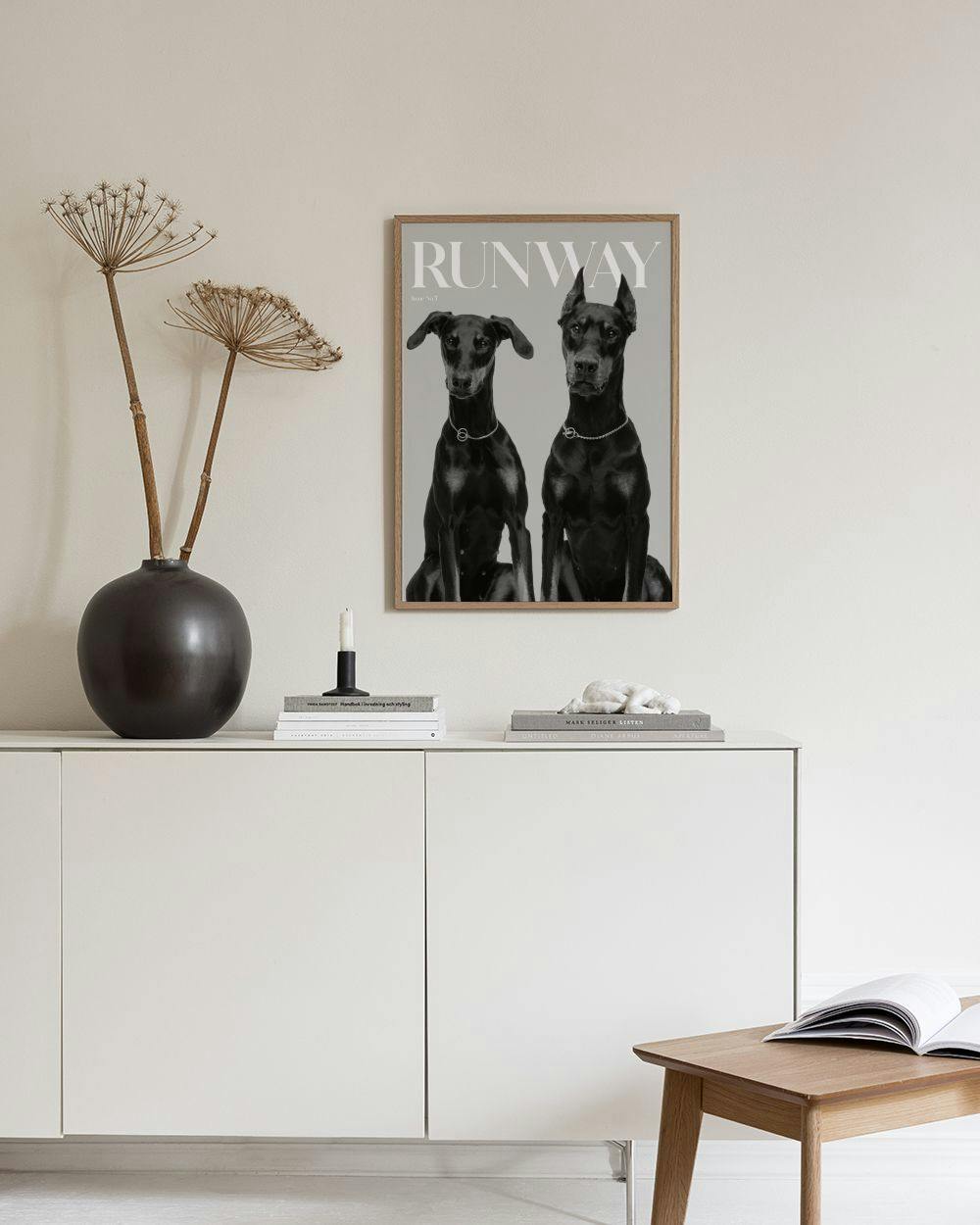 Affiche Runway en noir et blanc de deux dobermans, accrochée au-dessus dun canapé beige dans un salon moderne.