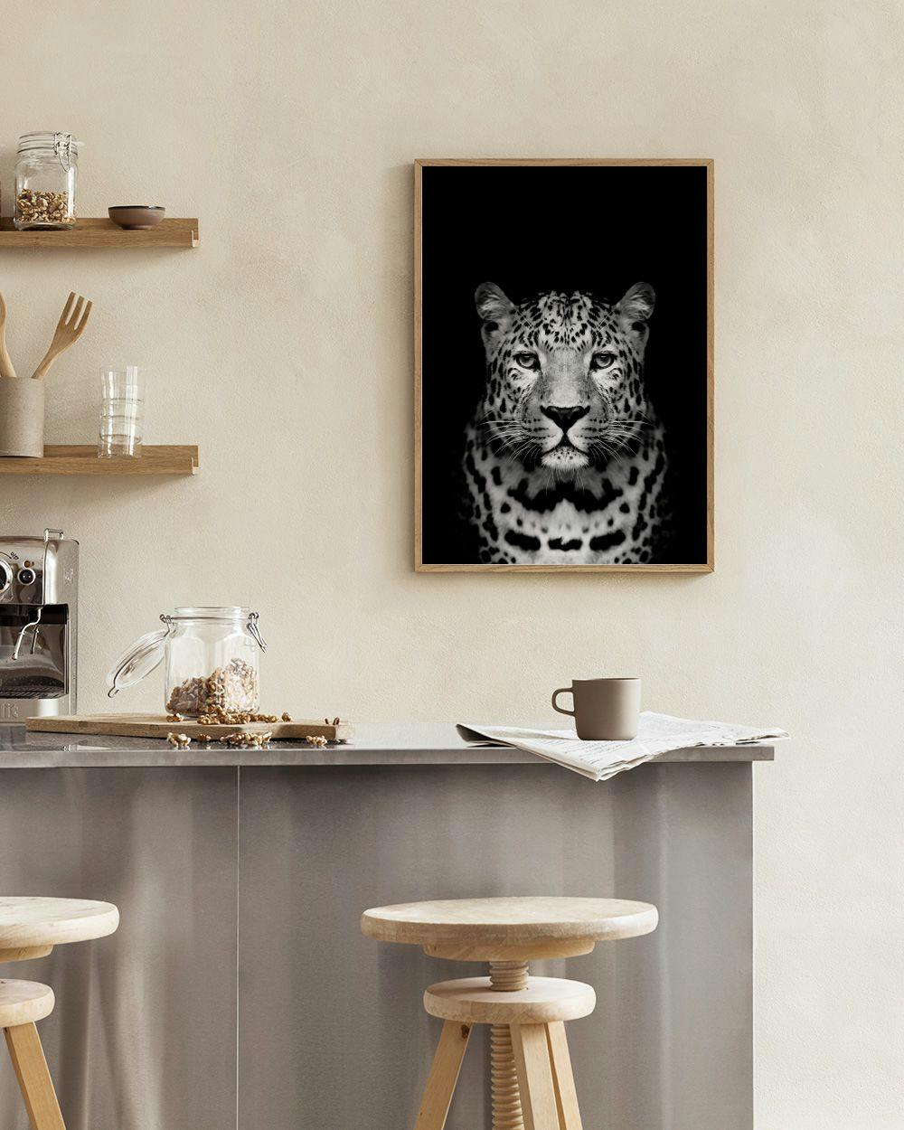 Affiche en noir et blanc dun léopard, suspendue au-dessus dun pouf bleu foncé dans un intérieur moderne.