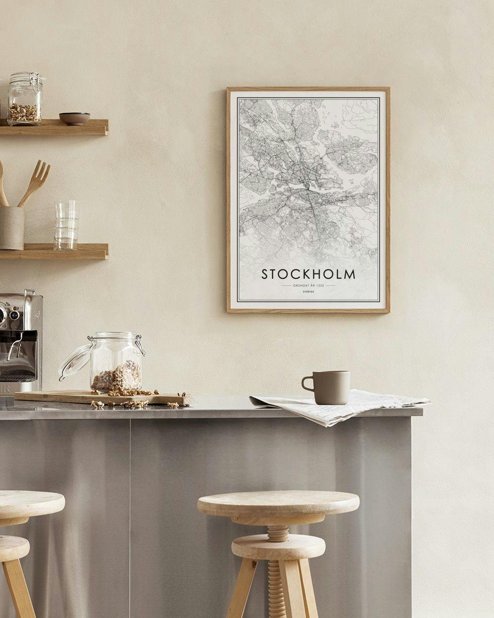 Affiche carte de Stockholm en noir et blanc dans une pièce aux murs gris, avec un pouf bleu et or.