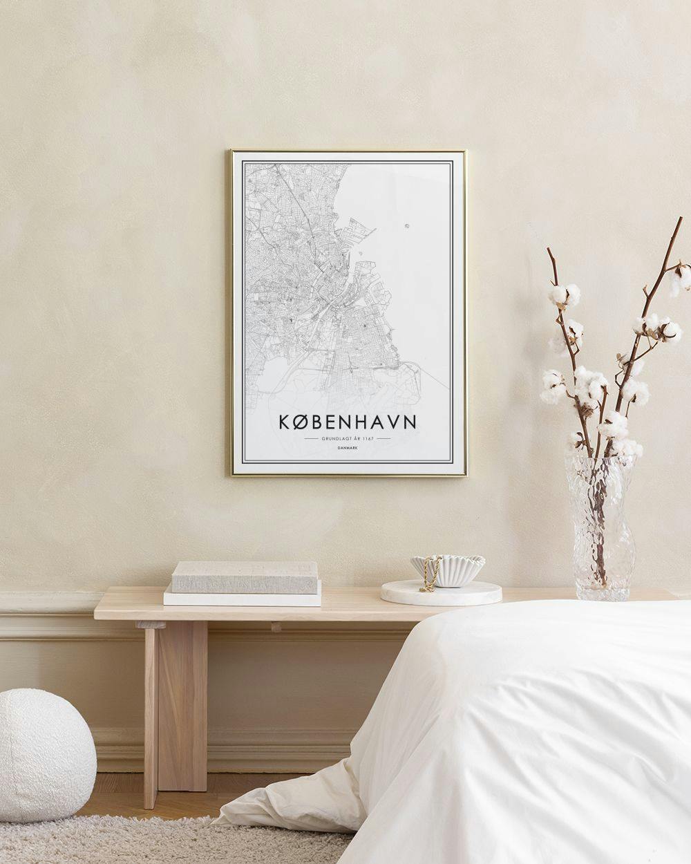 Affiche de la carte de Copenhague en noir et blanc, posée sur un meuble à côté dun cactus et dune bougie.