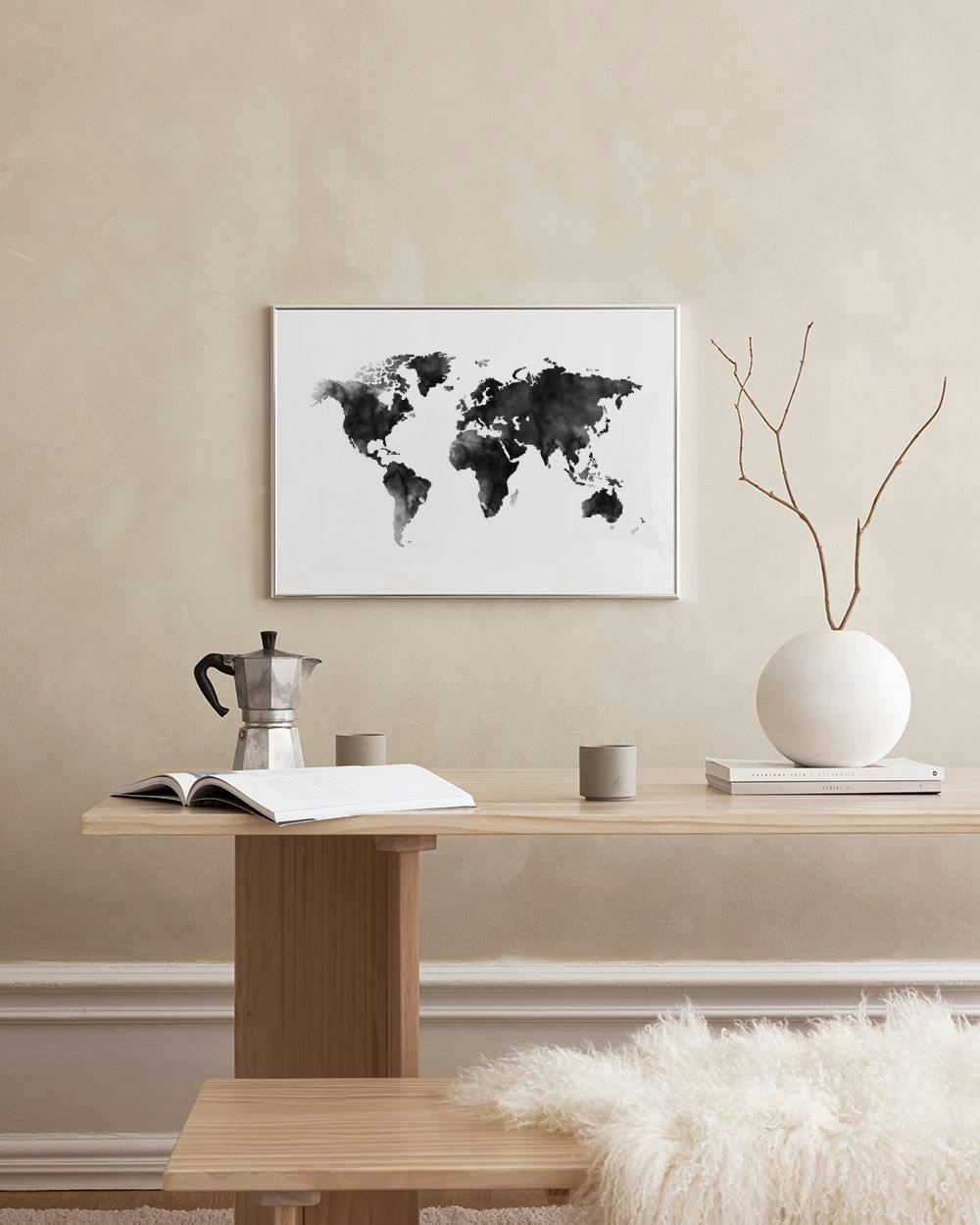 Affiche carte du monde en noir et blanc effet aquarelle, suspendue sur un mur vert foncé au-dessus dune table basse.