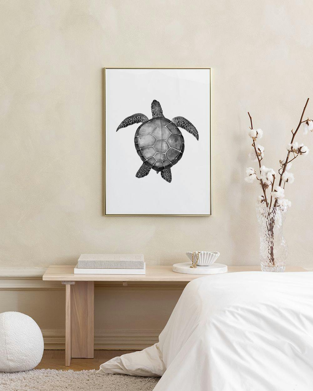 Affiche dune tortue de mer noire et blanche, accrochée au-dessus dun tabouret en liège avec des vases roses.