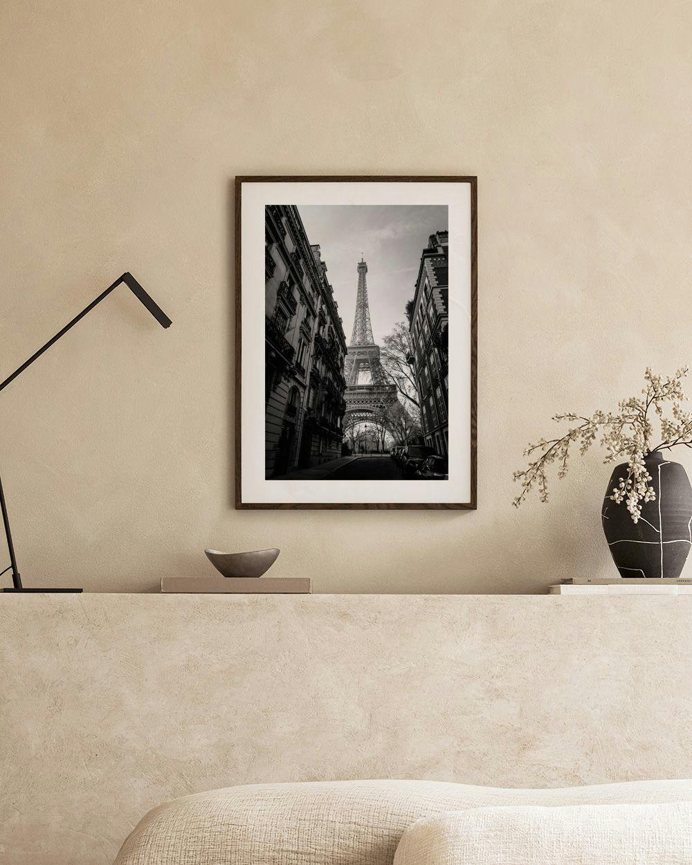 Affiche en noir et blanc de la Tour Eiffel vue dune rue parisienne, exposée dans un intérieur moderne.