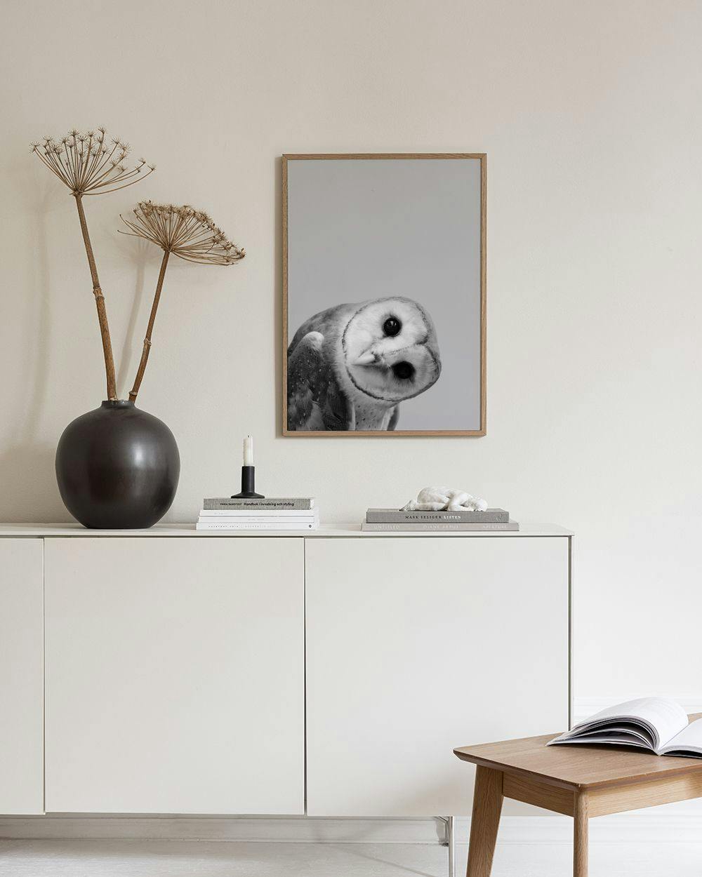 Affiche dun hibou noir et blanc avec la tête inclinée, accrochée au-dessus dun buffet blanc.