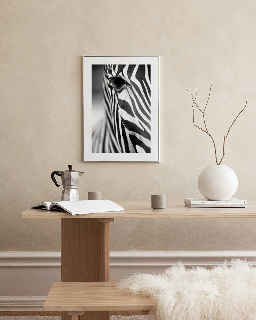 Affiche zèbre noir et blanc, accrochée au-dessus de tables basses avec vases dorés dans un salon moderne.