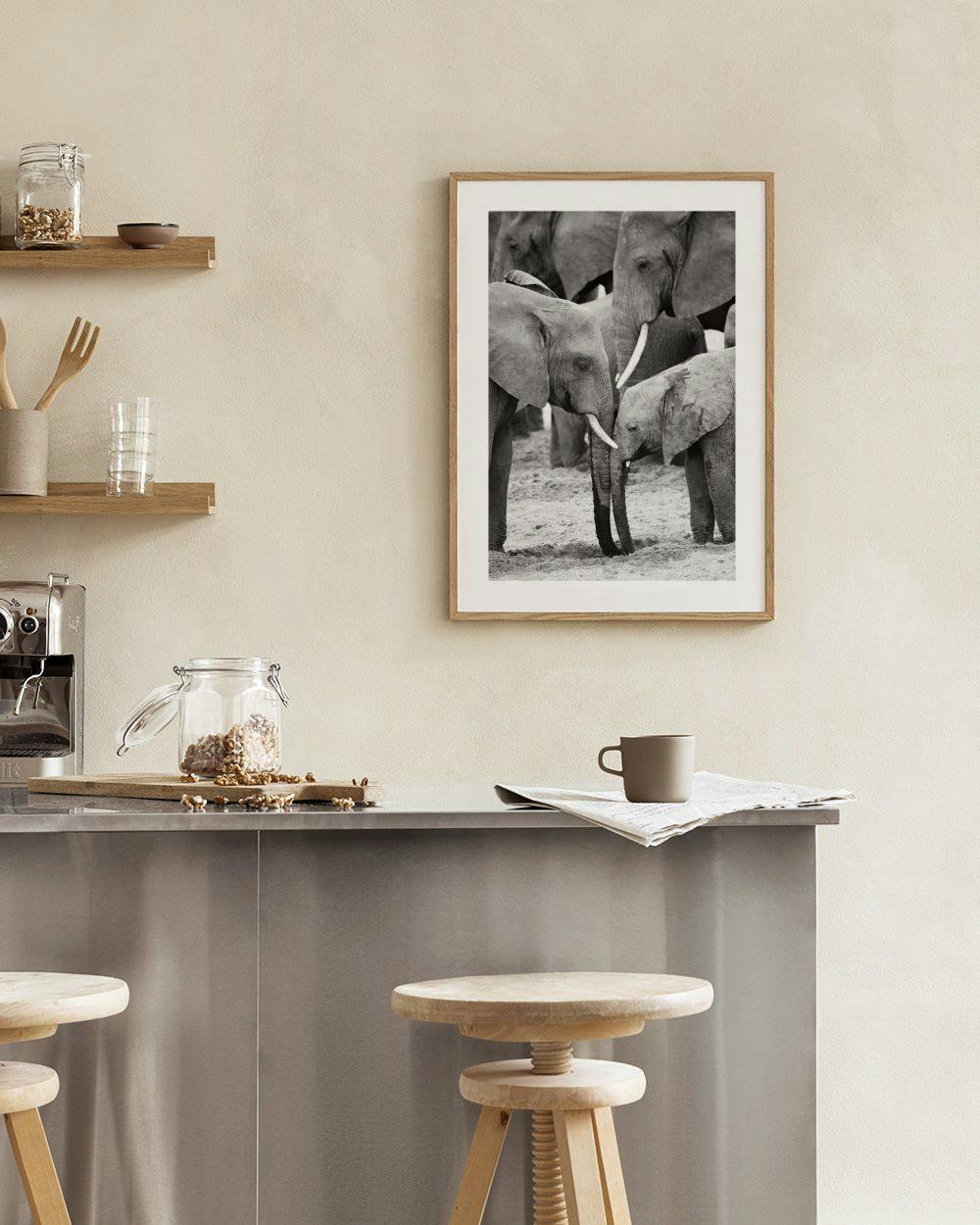 Affiche en noir et blanc déléphants dAfrique avec un éléphanteau, accrochée au-dessus dun fauteuil gris dans un salon moderne.