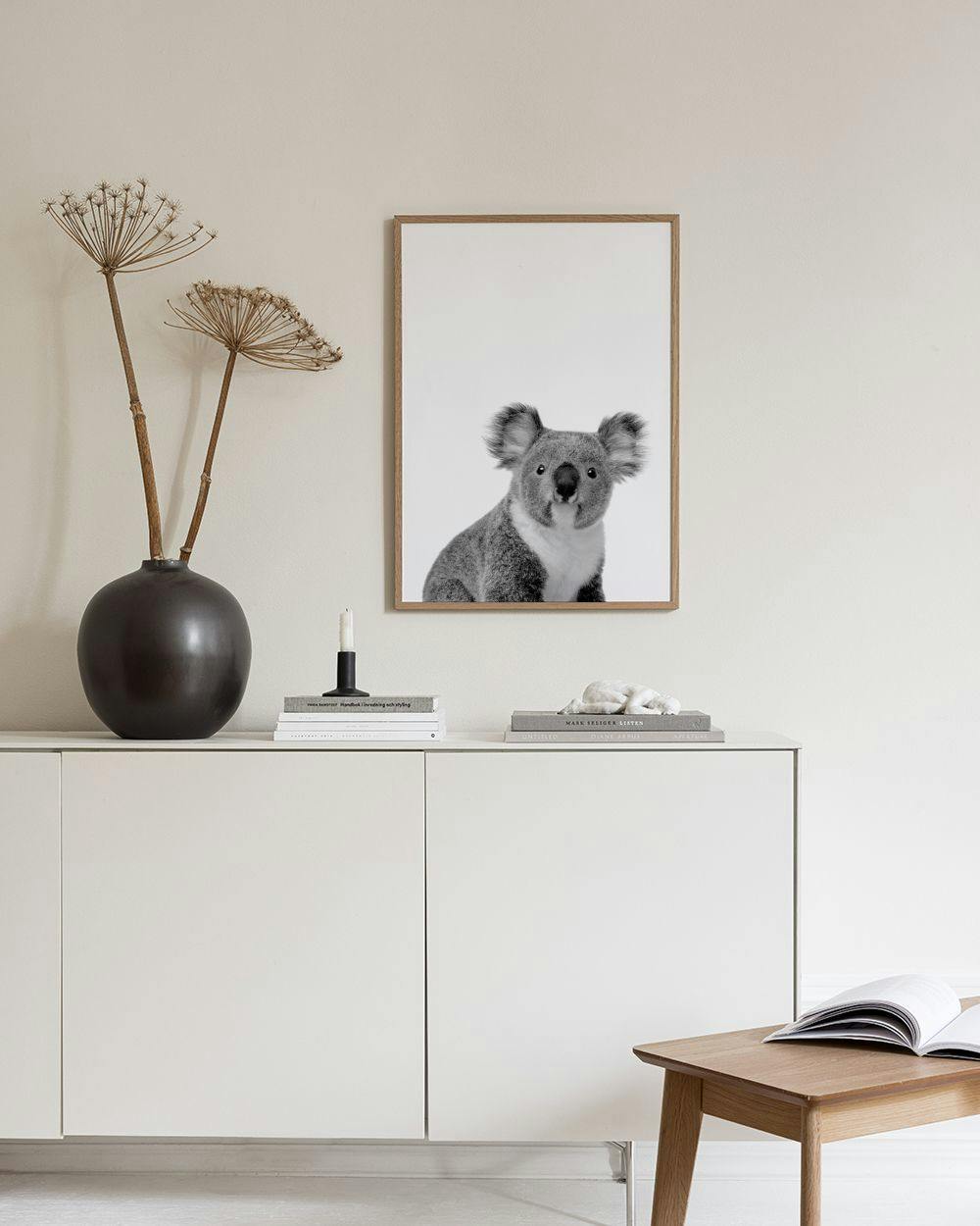 Affiche en noir et blanc dun bébé koala, accrochée au-dessus dun bureau avec une chaise et un vase.