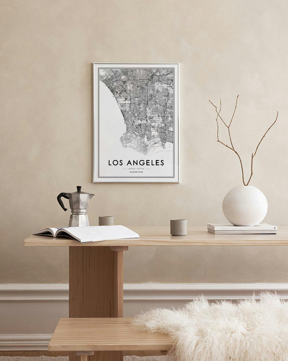 Affiche carte de Los Angeles en noir et blanc, accrochée à un treillis mural noir, avec une plante et une chaise.