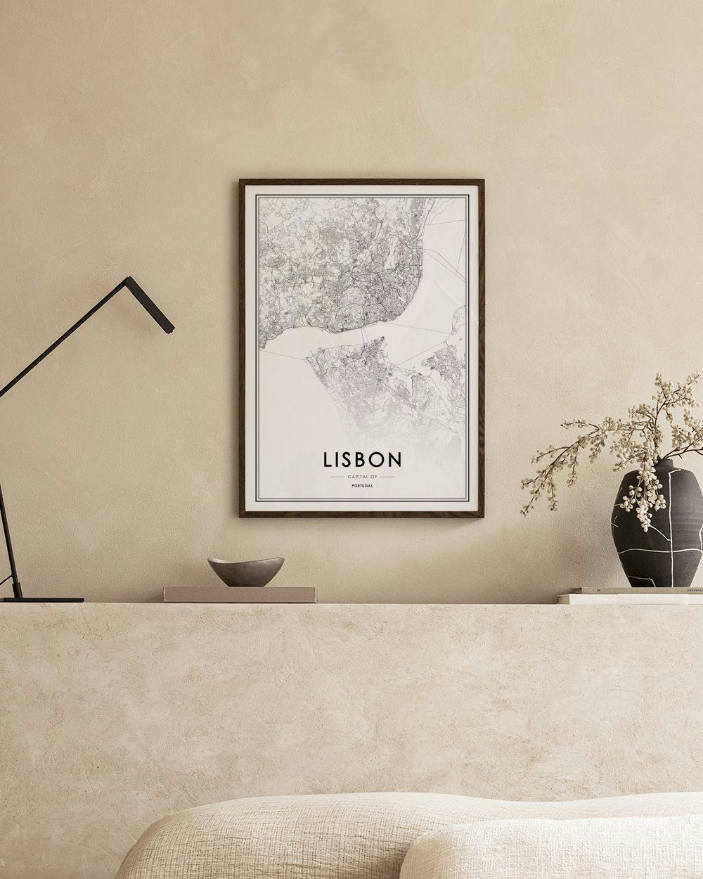 Affiche de la carte de Lisbonne en noir et blanc, accrochée au-dessus dune console noire avec des livres et une plante.