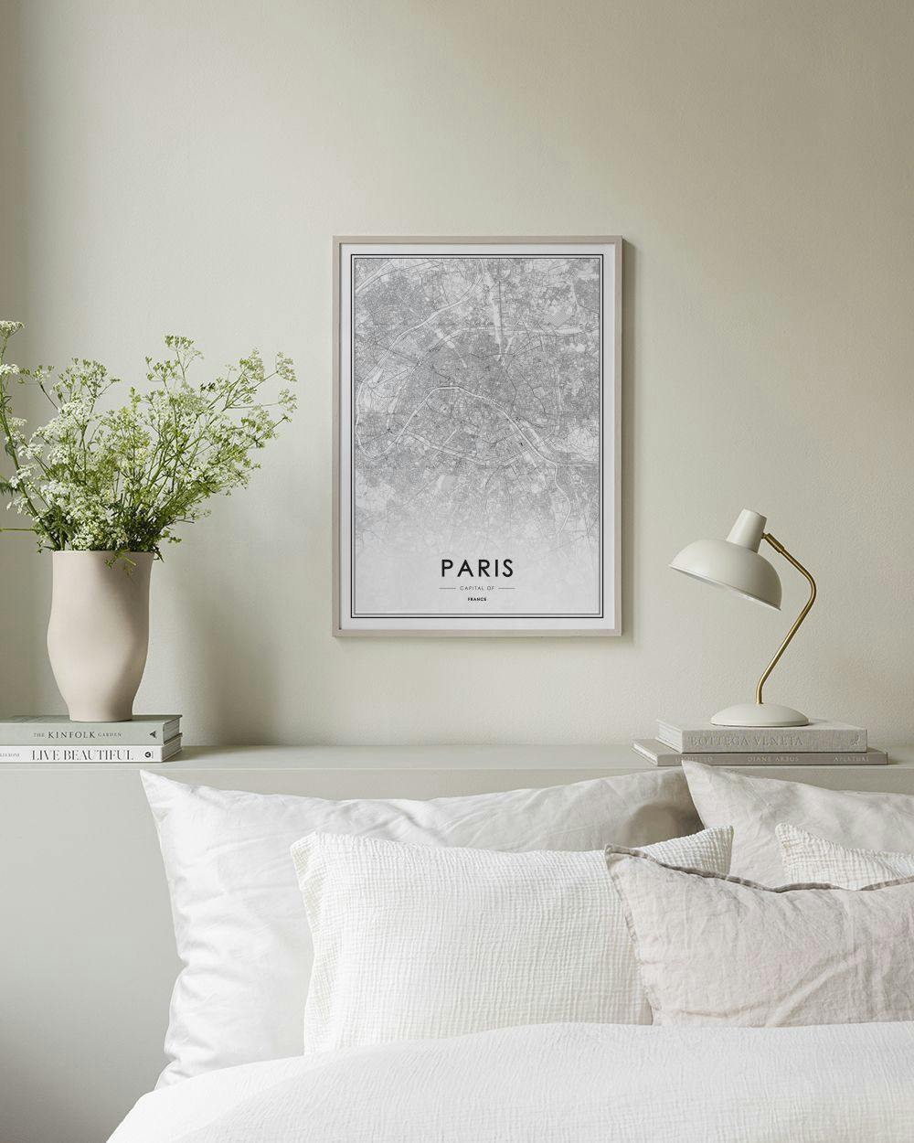 Affiche carte de Paris en noir et blanc posée sur un meuble blanc, avec un cactus et un bougeoir.