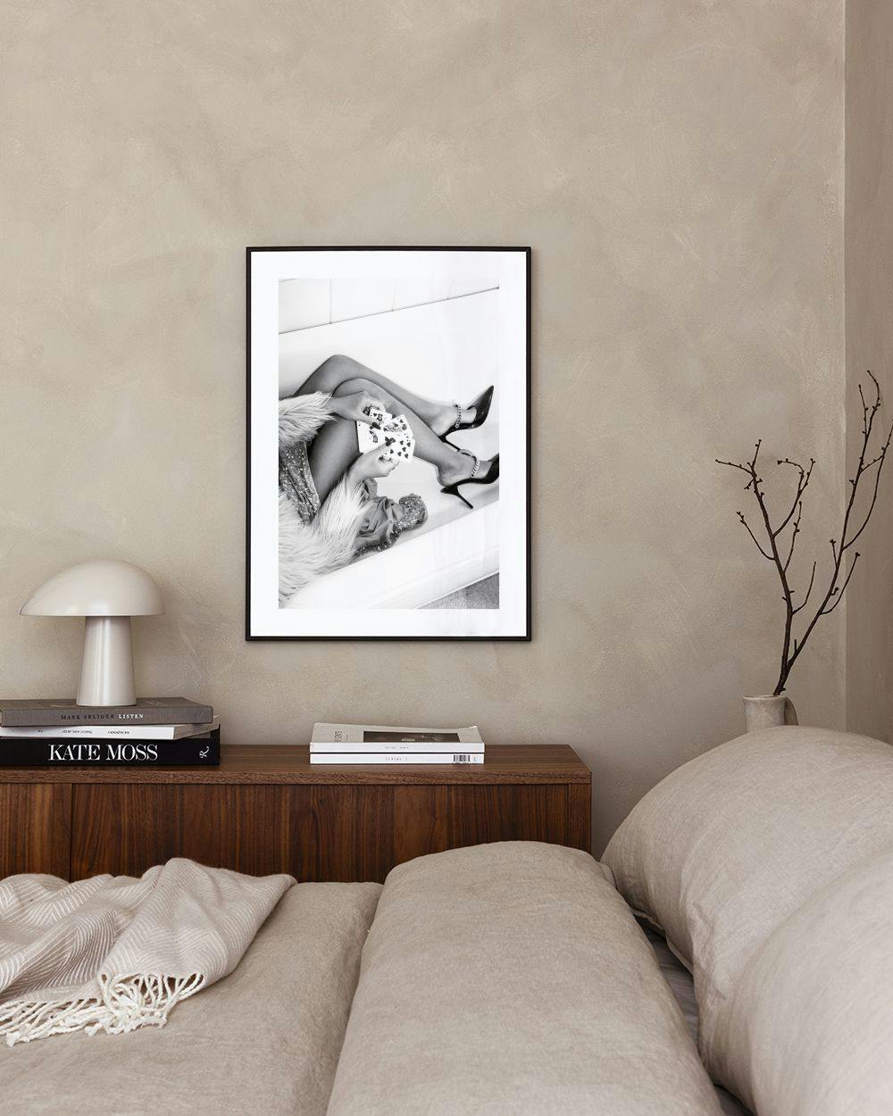 Affiche en noir et blanc de jambes féminines tenant des cartes, accrochée au-dessus dun banc rose.