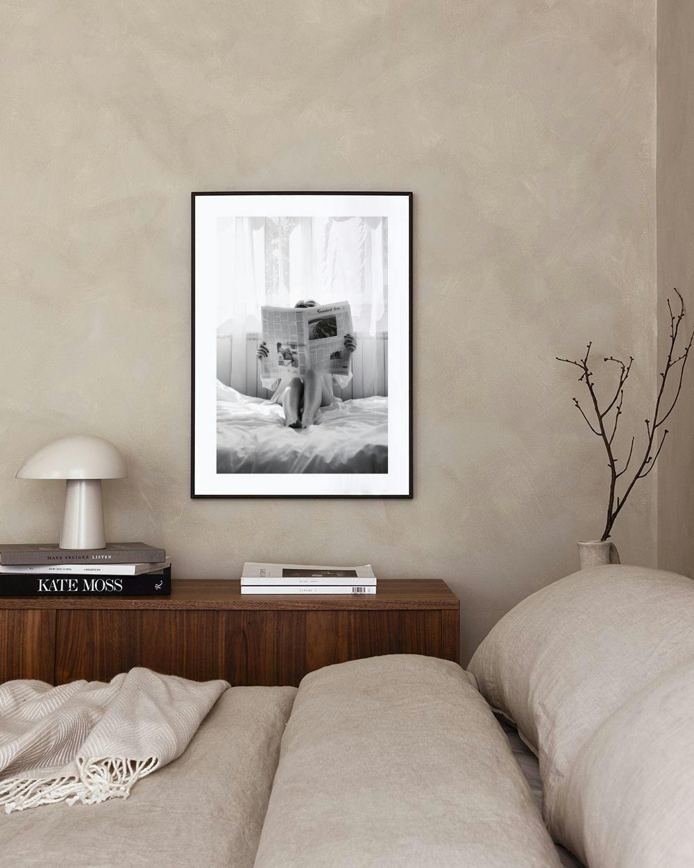 Affiche en noir et blanc dune personne lisant un journal dans un lit, exposée dans une chambre.