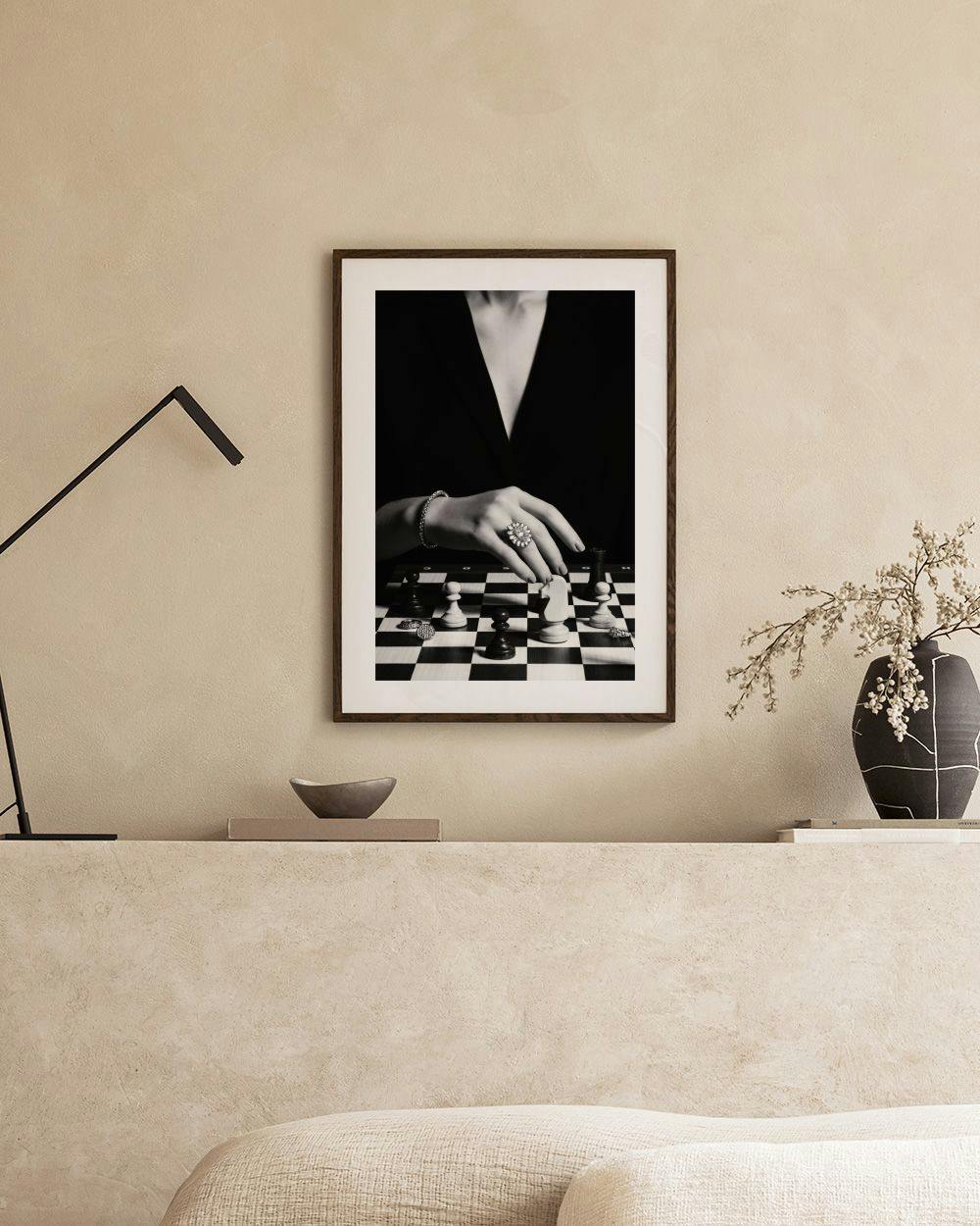 Affiche noir et blanc dune main jouant aux échecs, accrochée au mur dans une pièce moderne.