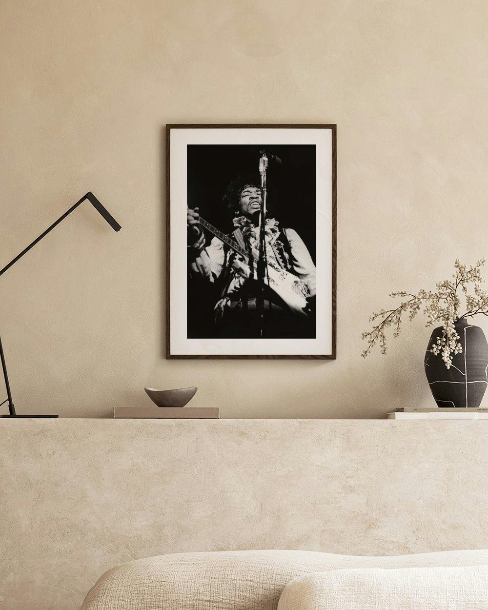 Affiche noire et blanche de Jimi Hendrix jouant de la guitare, accrochée dans un salon moderne.