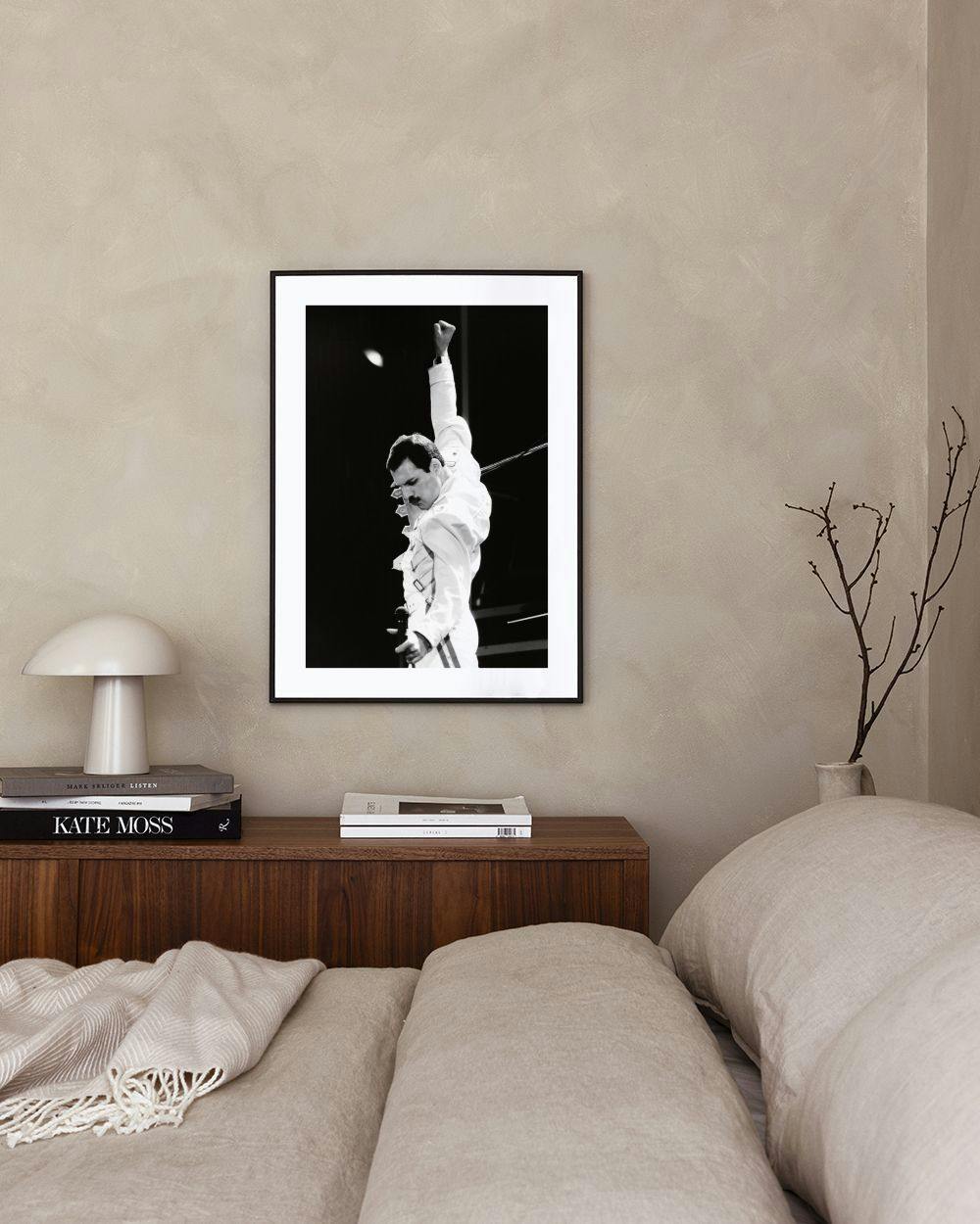 Affiche en noir et blanc de Freddie Mercury, bras levé, accrochée dans un salon moderne.