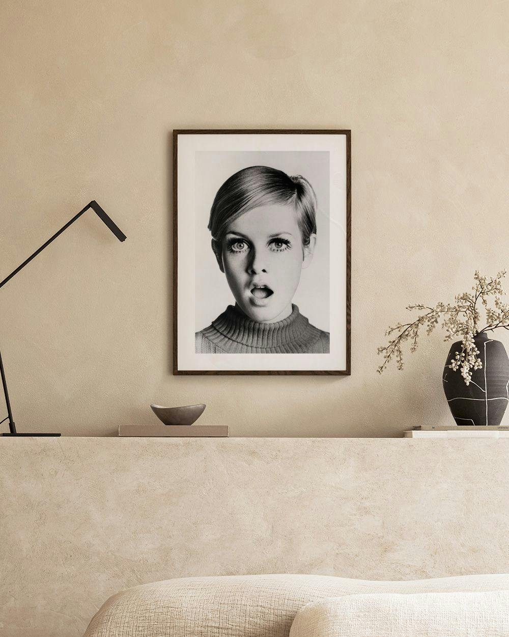 Affiche en noir et blanc de Twiggy, bouche ouverte, accrochée au-dessus dun banc en béton dans une pièce lumineuse.
