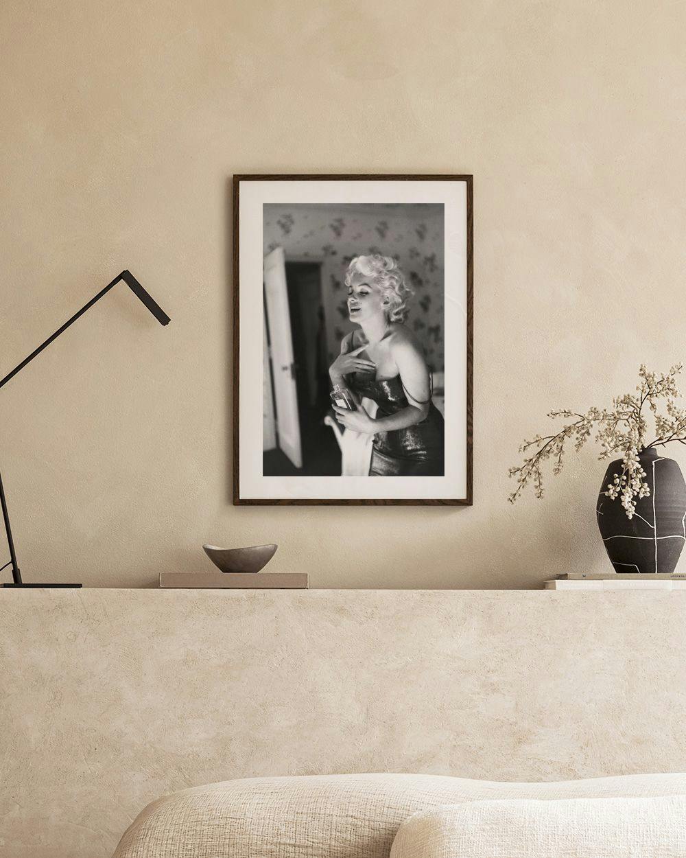 Affiche noir et blanc de Marilyn Monroe souriante, suspendue dans un salon gris scandinave au-dessus dun meuble blanc.