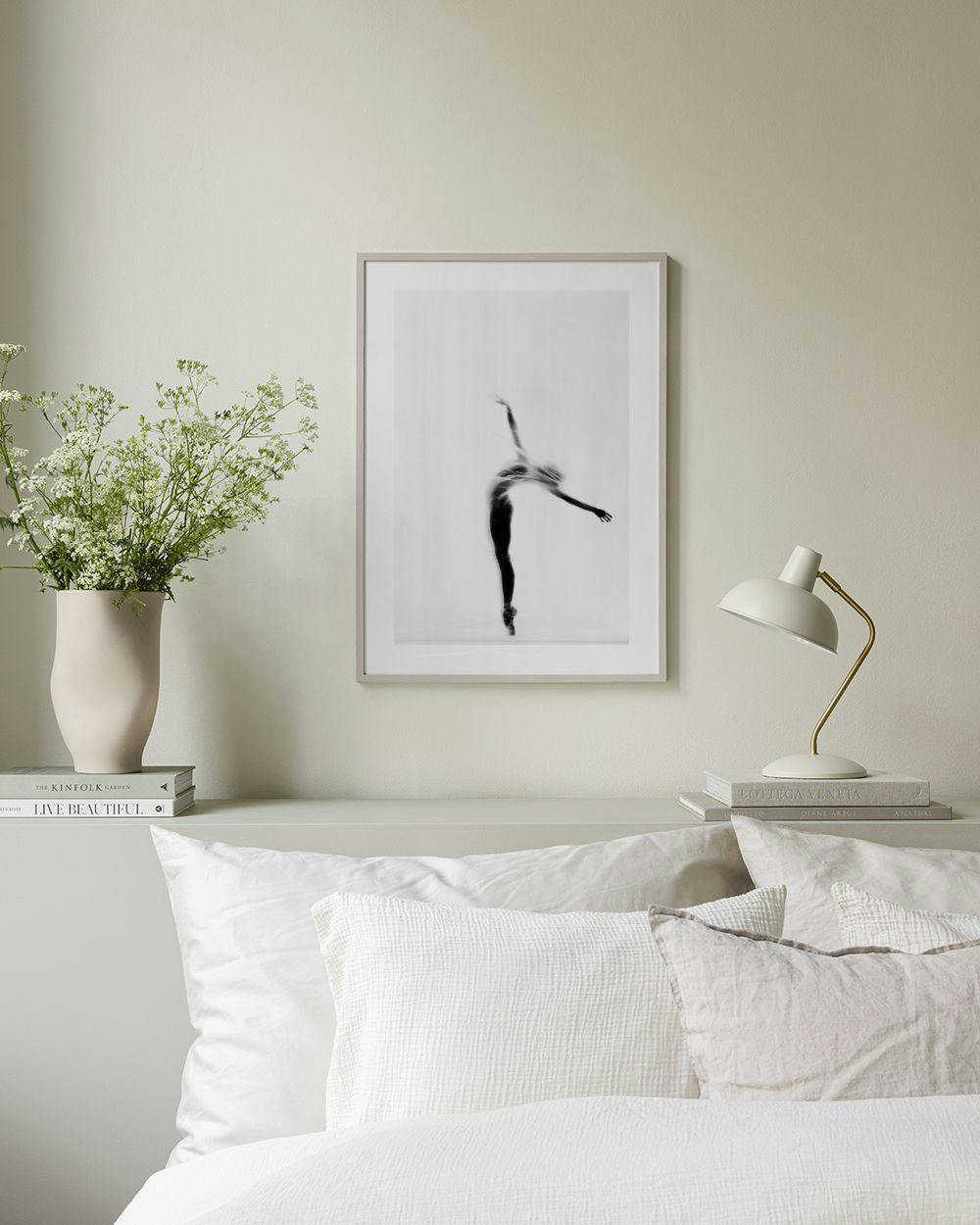 Affiche en noir et blanc dune danseuse classique en équilibre, suspendue au-dessus dune étagère noire avec des livres et une pla