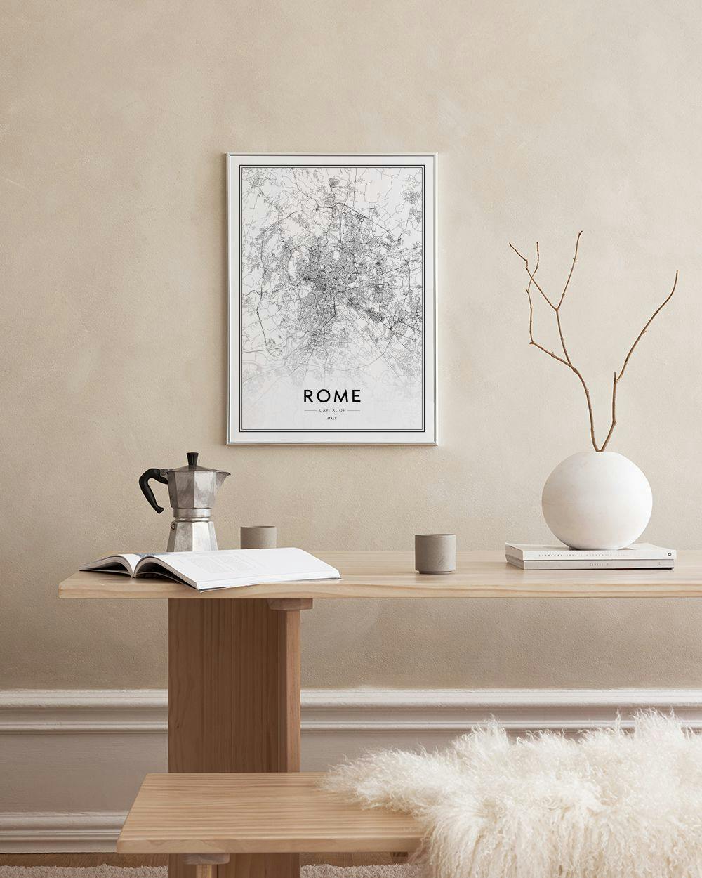 Affiche de la carte de Rome en noir et blanc, affichée au-dessus dune console noire avec des livres et une plante.