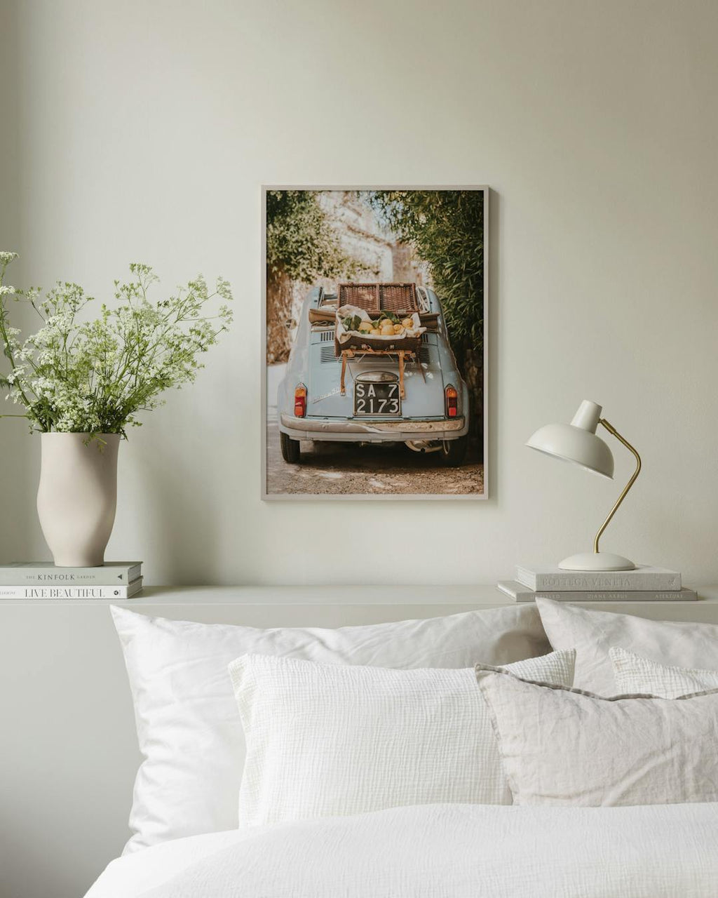 Affiche dune Fiat 500 bleue avec un panier de citrons, suspendue au-dessus dun lit dans une chambre lumineuse.