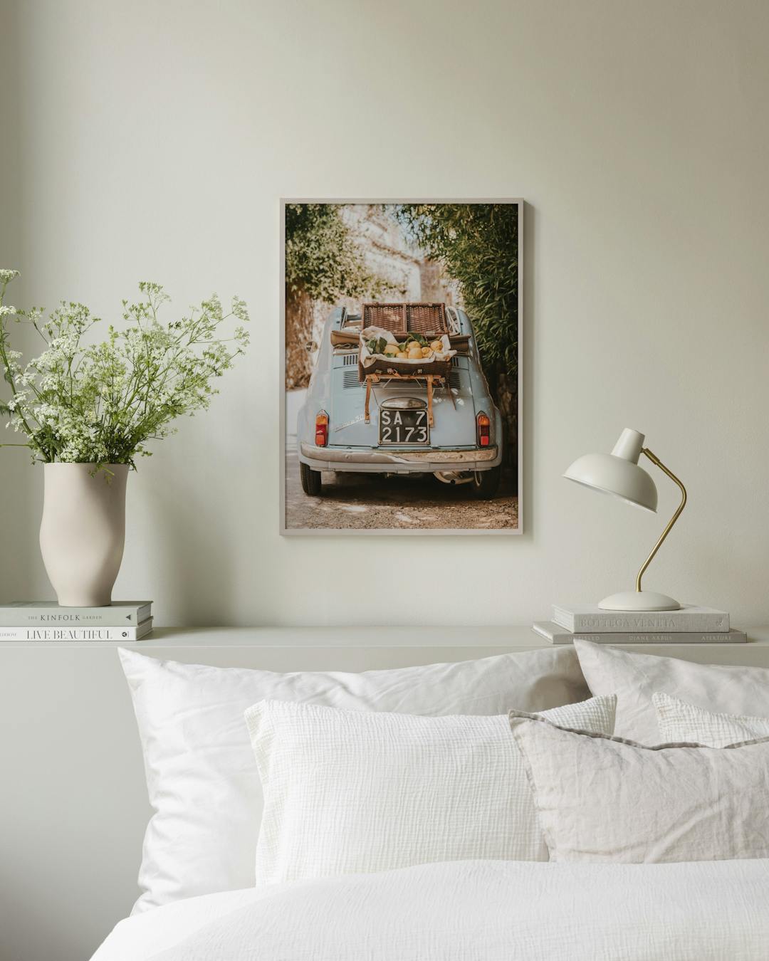 Affiche dune Fiat 500 bleue avec un panier de citrons, suspendue au-dessus dun lit dans une chambre lumineuse.