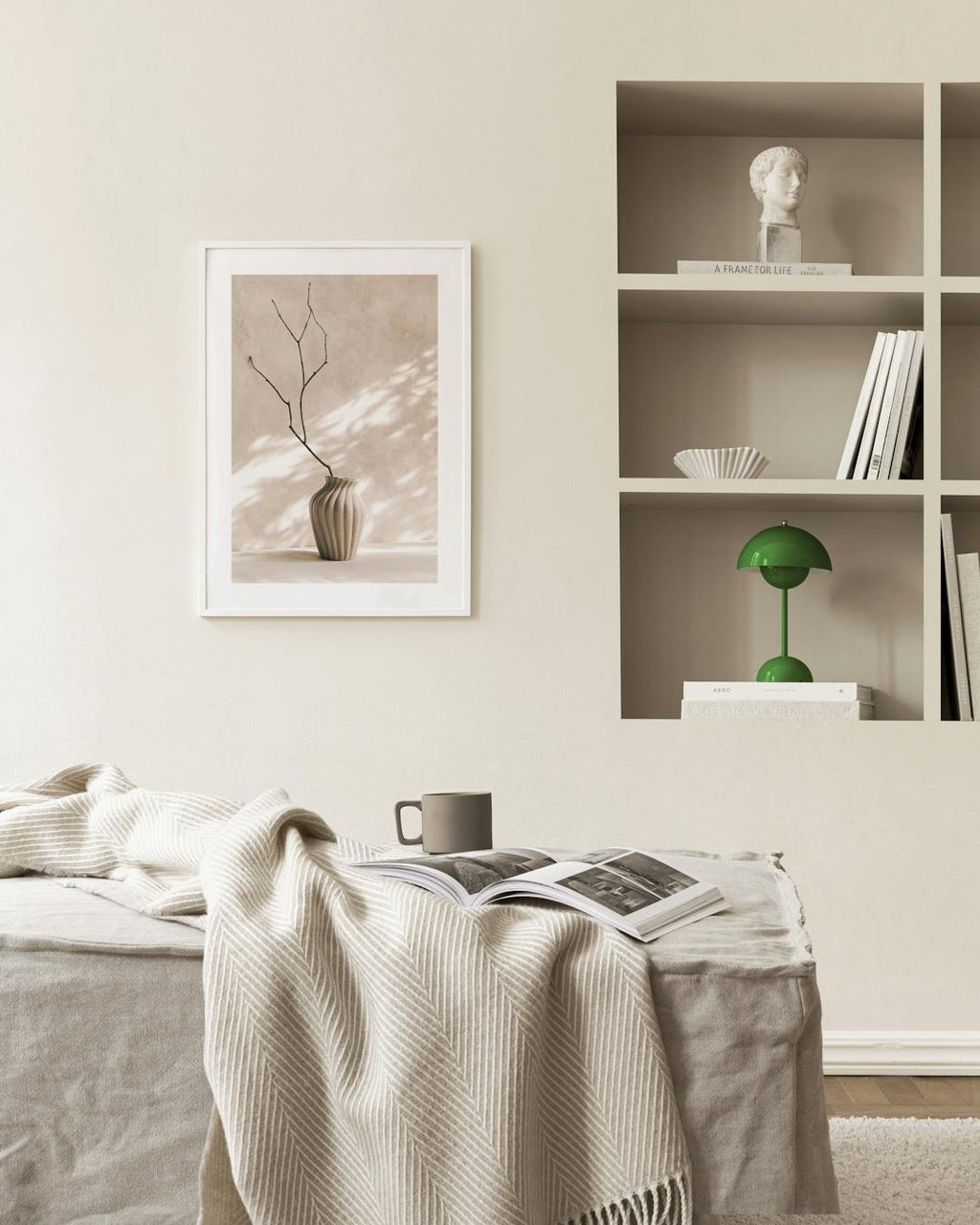 Affiche dun vase beige strié avec une branche sèche, suspendue dans une pièce aux murs clairs.