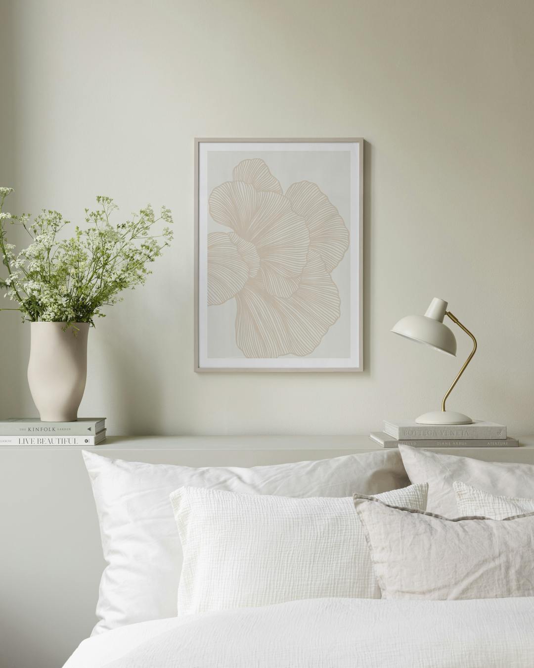 Affiche murale aux motifs floraux beiges et lignes fines, dans un intérieur clair avec coussins et couverture.
