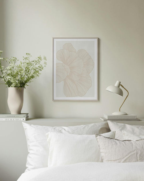 Affiche murale aux motifs floraux beiges et lignes fines, dans un intérieur clair avec coussins et couverture.