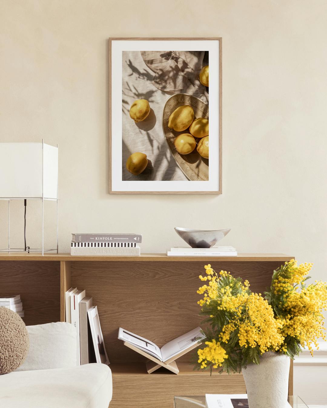 Affiche de citrons jaunes sur un plat, accrochée au-dessus dun buffet en rotin dans un salon lumineux.