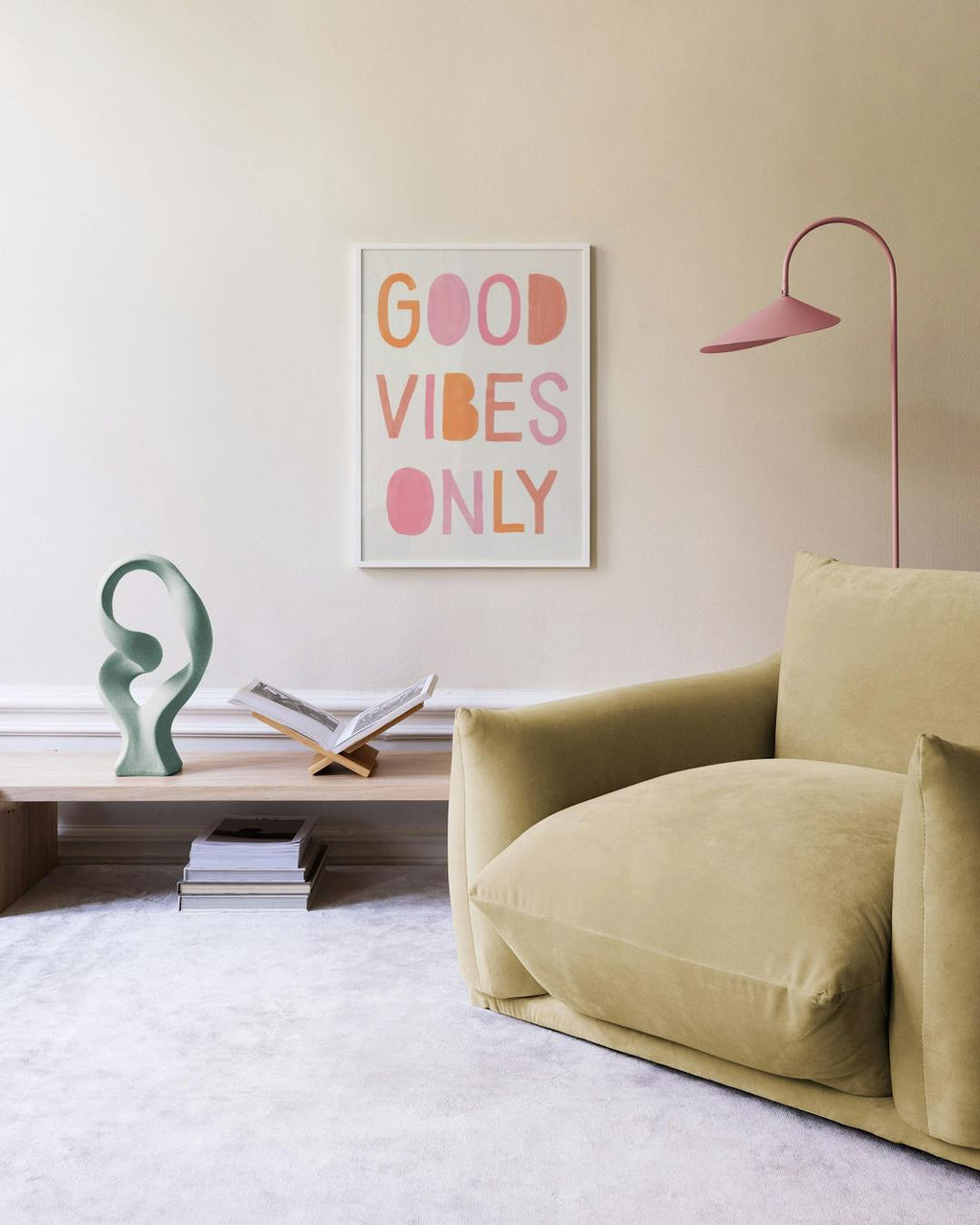 Affiche GOOD VIBES ONLY aux lettres roses et oranges, accrochée au mur au-dessus dune commode blanche avec des livres et une lam
