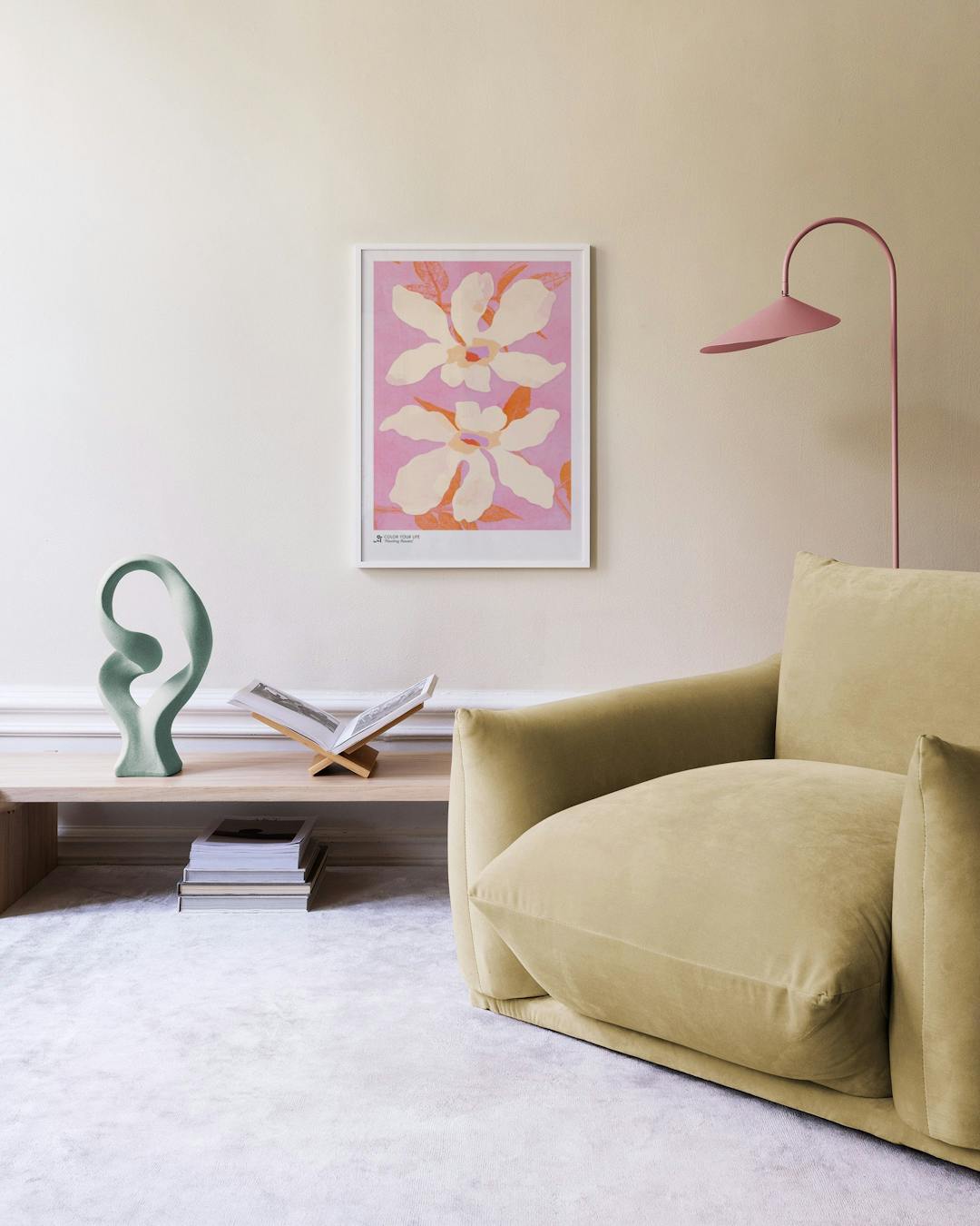 Affiche de deux fleurs blanches aux pistils colorés sur fond rose, suspendue au-dessus dun meuble en rotin clair.